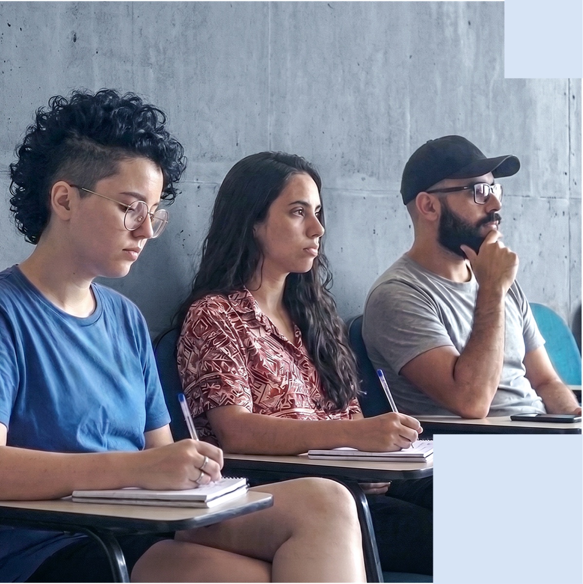 Tre studenti seguono una lezione seduti ai banchi